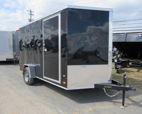 a black and silver trailer is parked in a parking lot .