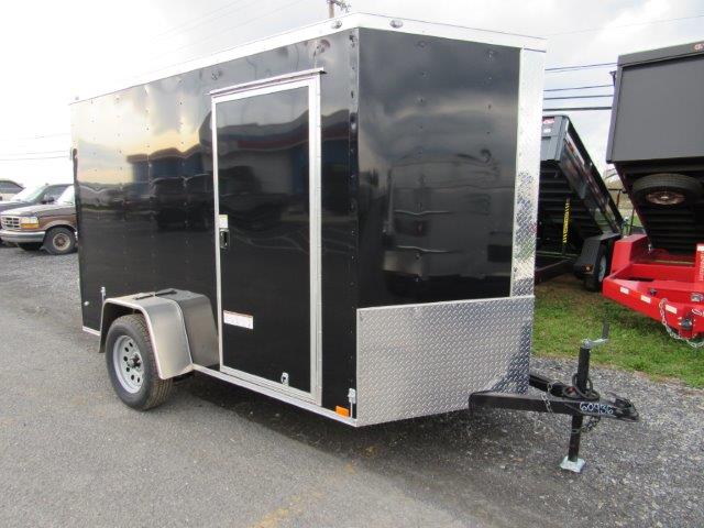 a black trailer is parked on the side of the road next to a dumpster .