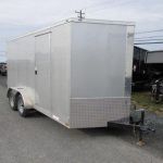 a white trailer is parked on the side of the road .