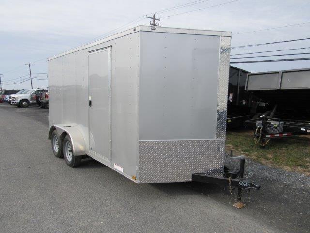 a white trailer is parked on the side of the road .