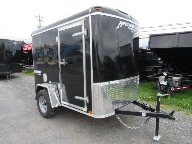 a black trailer is parked on the side of the gravel parking lot