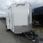 a white trailer is parked on the side of the road in a parking lot .