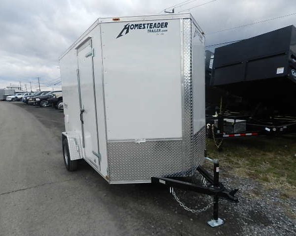 a white trailer is parked on the side of the road in a parking lot .