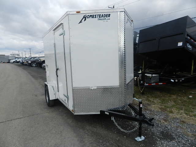 a white trailer is parked on the side of the road in a parking lot .