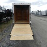 a Homesteader trailer with a wooden ramp parked on the side of the road