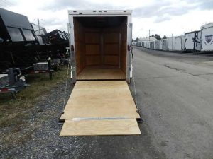 a Homesteader trailer with a wooden ramp parked on the side of the road