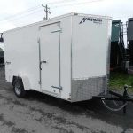 a white trailer is parked on the side of the road .
