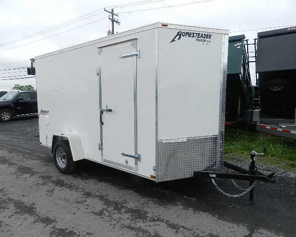 a white trailer is parked on the side of the road .