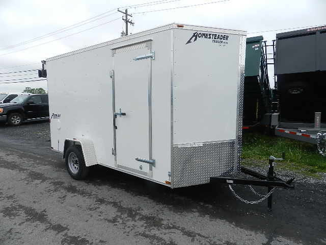 a white trailer is parked on the side of the road .