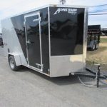 a black and silver trailer is parked on the side of the road .