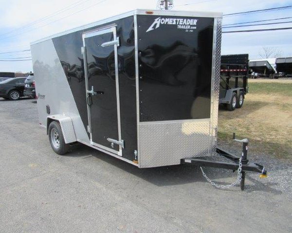 a black and silver trailer is parked on the side of the road .