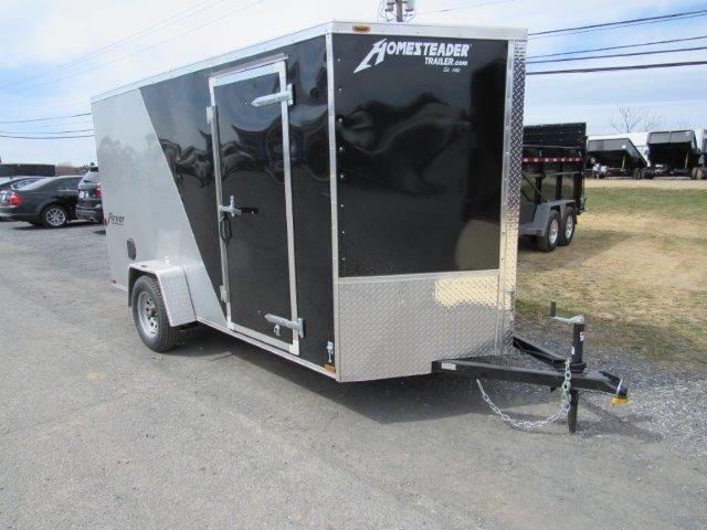 a black and silver trailer is parked on the side of the road .