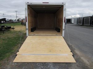 a white trailer with the door open and a wooden ramp