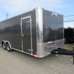 a black and silver trailer is parked on the side of the road .