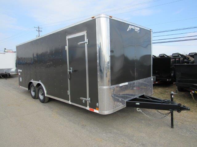a black and silver trailer is parked on the side of the road .