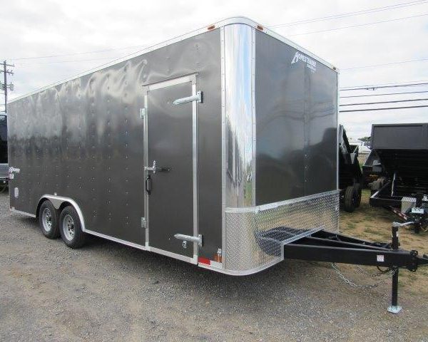 a black trailer is parked in a gravel lot