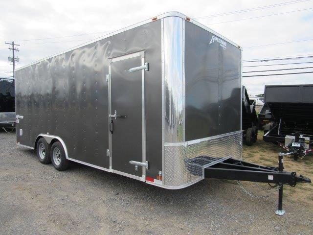 a black trailer is parked in a gravel lot