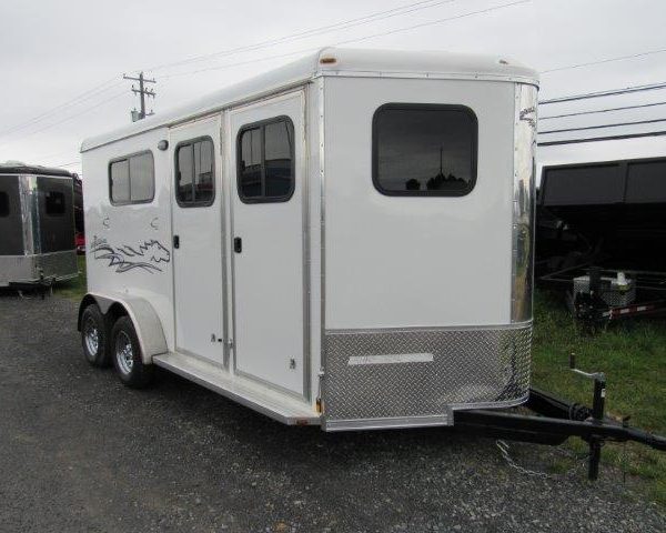 a white horse trailer is parked on the side of the road