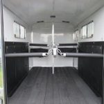 the inside of a homesteader horse trailer with the doors open .