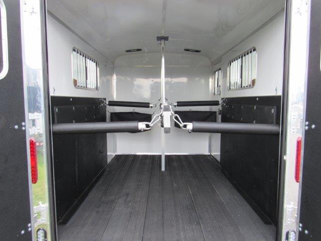 the inside of a homesteader horse trailer with the doors open .