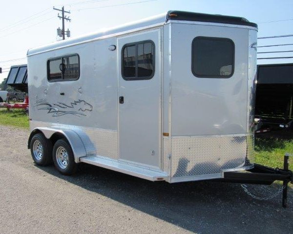 a white horse trailer is parked on the side of the road .