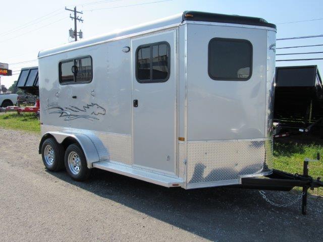 a white horse trailer is parked on the side of the road .