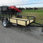a trailer with a wooden deck is parked on the side of the road .
