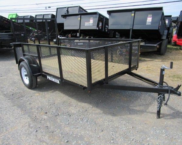 a trailer is parked in a gravel lot next to dumpsters .