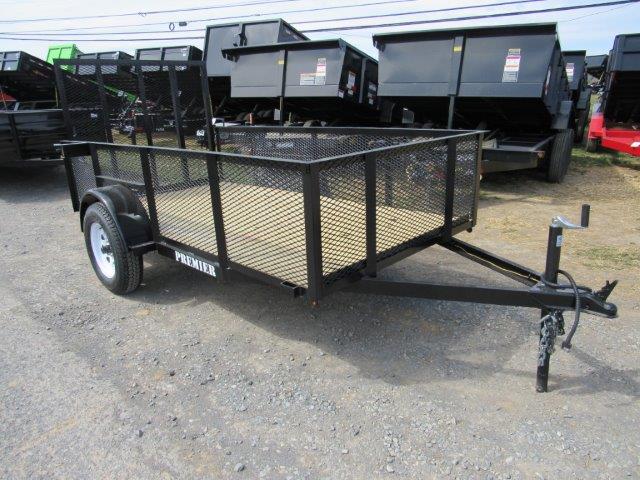 a trailer is parked in a gravel lot next to dumpsters .
