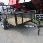 a black trailer is parked on the side of the road in front of a trailer dealership