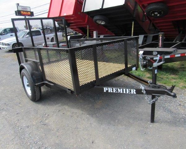 a black trailer is parked on the side of the road in front of a trailer dealership