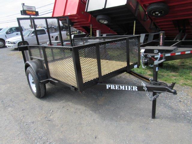 a black trailer is parked on the side of the road in front of a trailer dealership