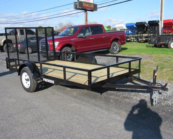 a black trailer with a wooden deck is parked on the side of the road