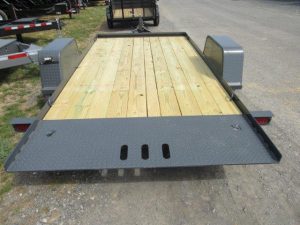 a trailer with a wooden deck is parked on the side of the road .