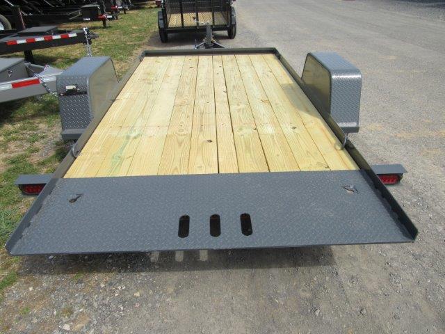 a trailer with a wooden deck is parked on the side of the road .