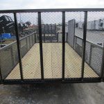 a trailer with a mesh fence and a wooden floor is parked on the side of the road .