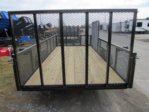 a trailer with a mesh fence and a wooden floor is parked on the side of the road .
