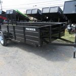 a black trailer parked next to a row of dump trailers