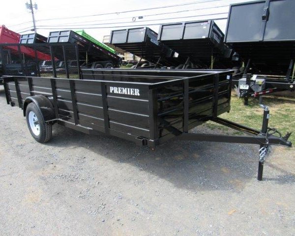 a black trailer parked next to a row of dump trailers