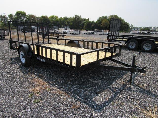 a trailer with a wooden deck is parked in a gravel lot .