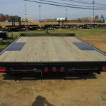a trailer with a wooden deck is parked in a field .