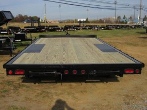 a trailer with a wooden deck is parked in a field .