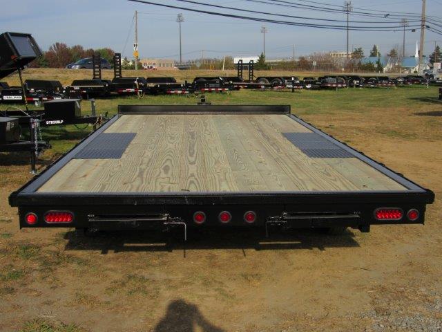 a trailer with a wooden deck is parked in a field .