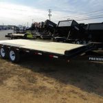 a Premier trailer with a wooden deck parked in a dirt lot