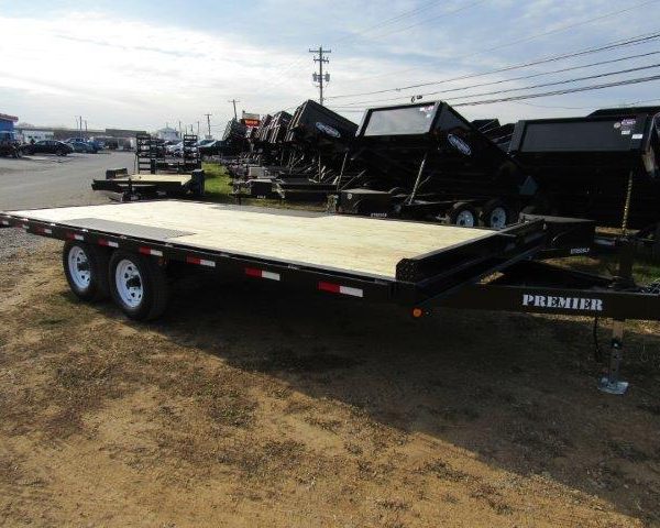 a Premier trailer with a wooden deck parked in a dirt lot