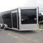 a black and silver trailer is parked on the side of the road .