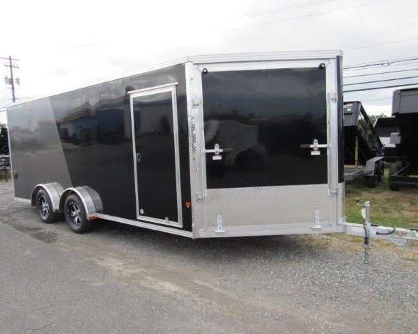 a black and silver trailer is parked on the side of the road .
