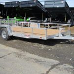 a silver trailer with a wooden deck is parked on the side of the road