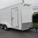 a white trailer is parked on the side of the road .