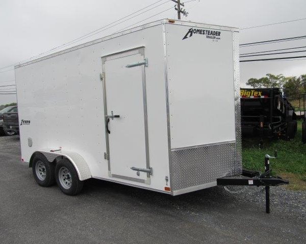 a white trailer is parked on the side of the road .